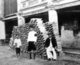 Thailand: Tin miners stand beside a pile of tin ingots stacked in front of a commercial shophouse in Phuket town, late 19th century